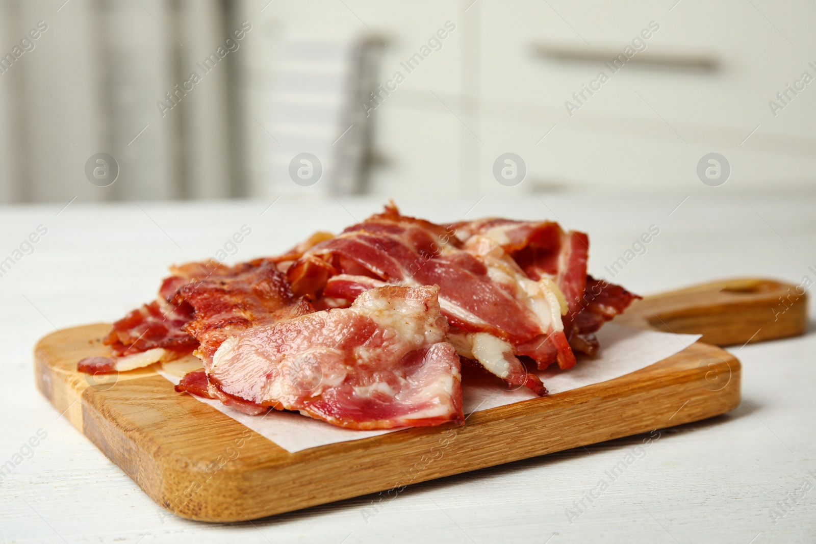 Photo of Slices of tasty fried bacon on white wooden table indoors