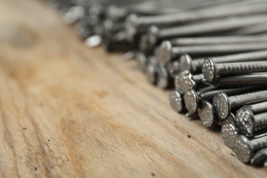 Photo of Many metal nails on wooden background, closeup. Space for text