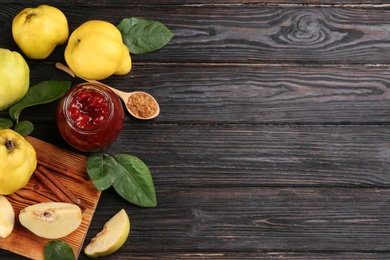 Delicious quince jam and fruits on black wooden table, flat lay. Space for text