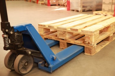 Modern manual forklift with wooden pallets in warehouse, closeup