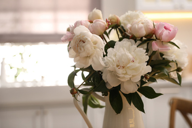 Beautiful peonies in vase against blurred background, closeup. Space for text