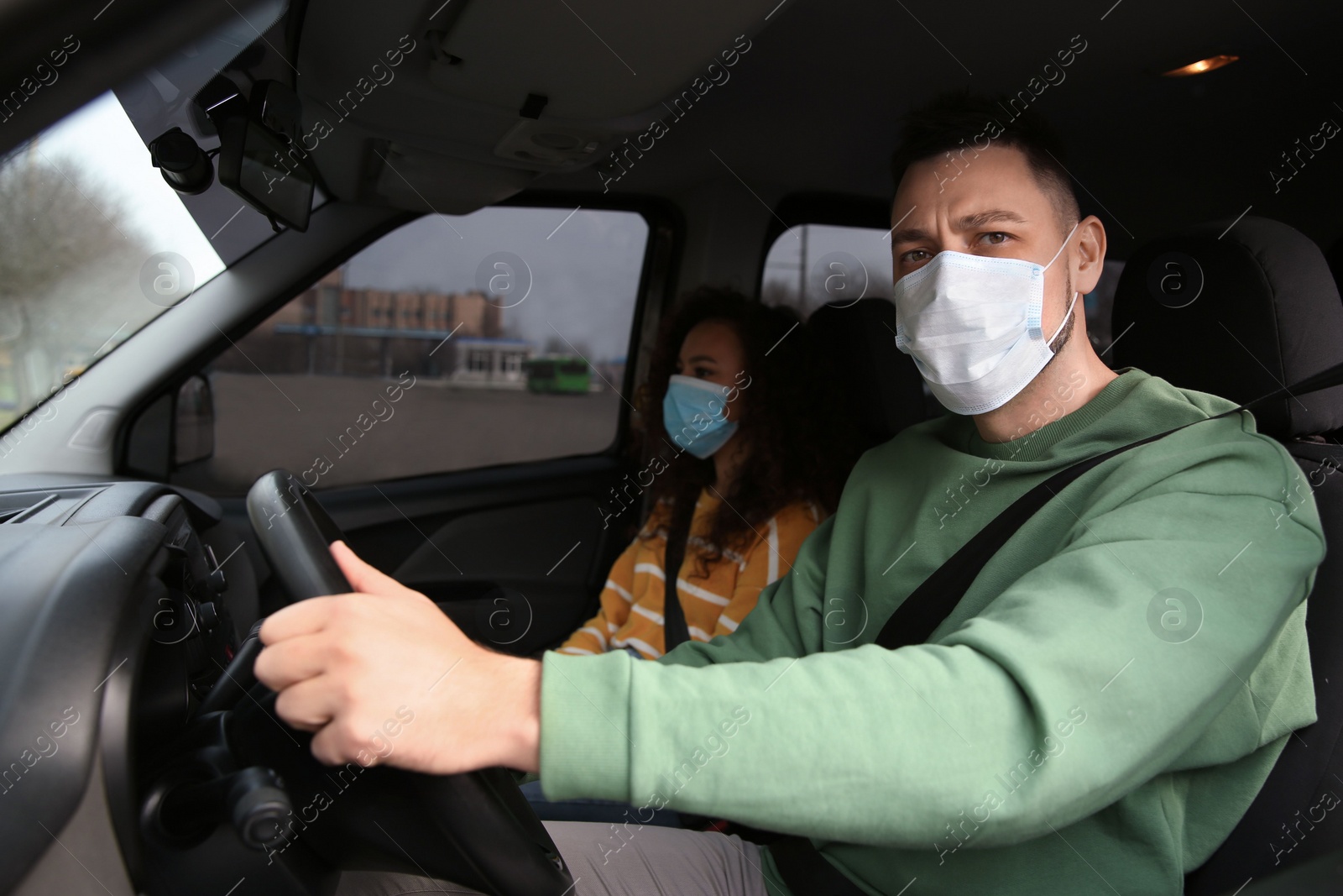 Photo of Couple with disposable masks in car. Virus protection