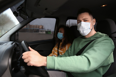 Photo of Couple with disposable masks in car. Virus protection