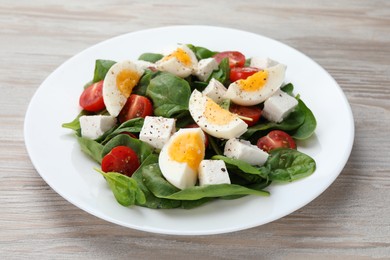 Photo of Delicious salad with boiled eggs, feta cheese and tomatoes on wooden table, closeup