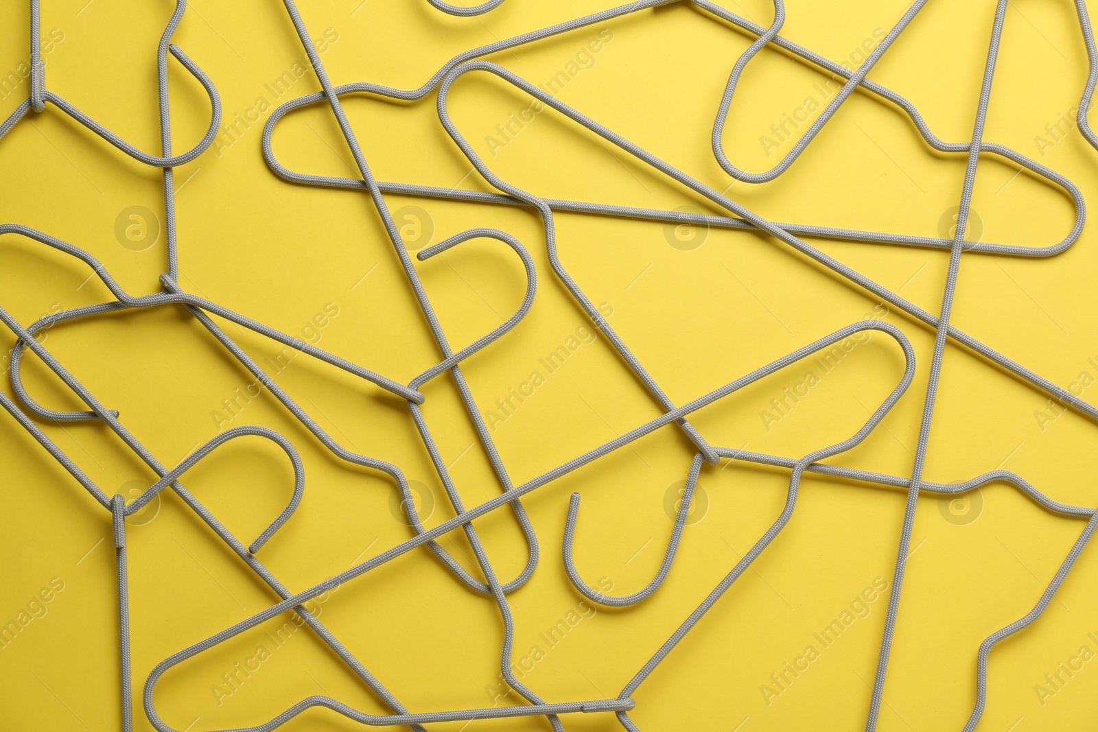 Photo of Empty hangers on yellow background, top view