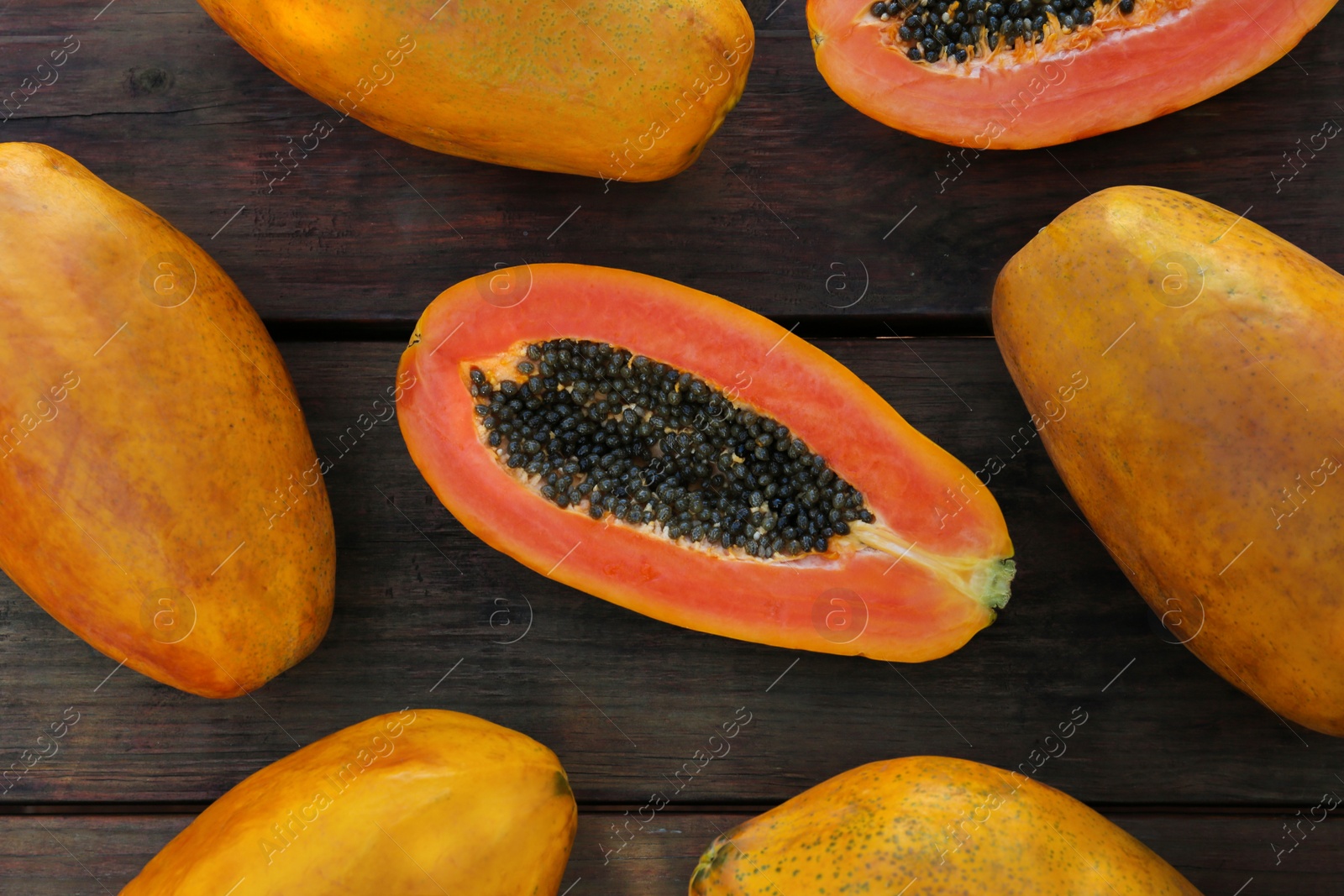 Photo of Fresh ripe cut and whole papaya fruits on wooden table, flat lay