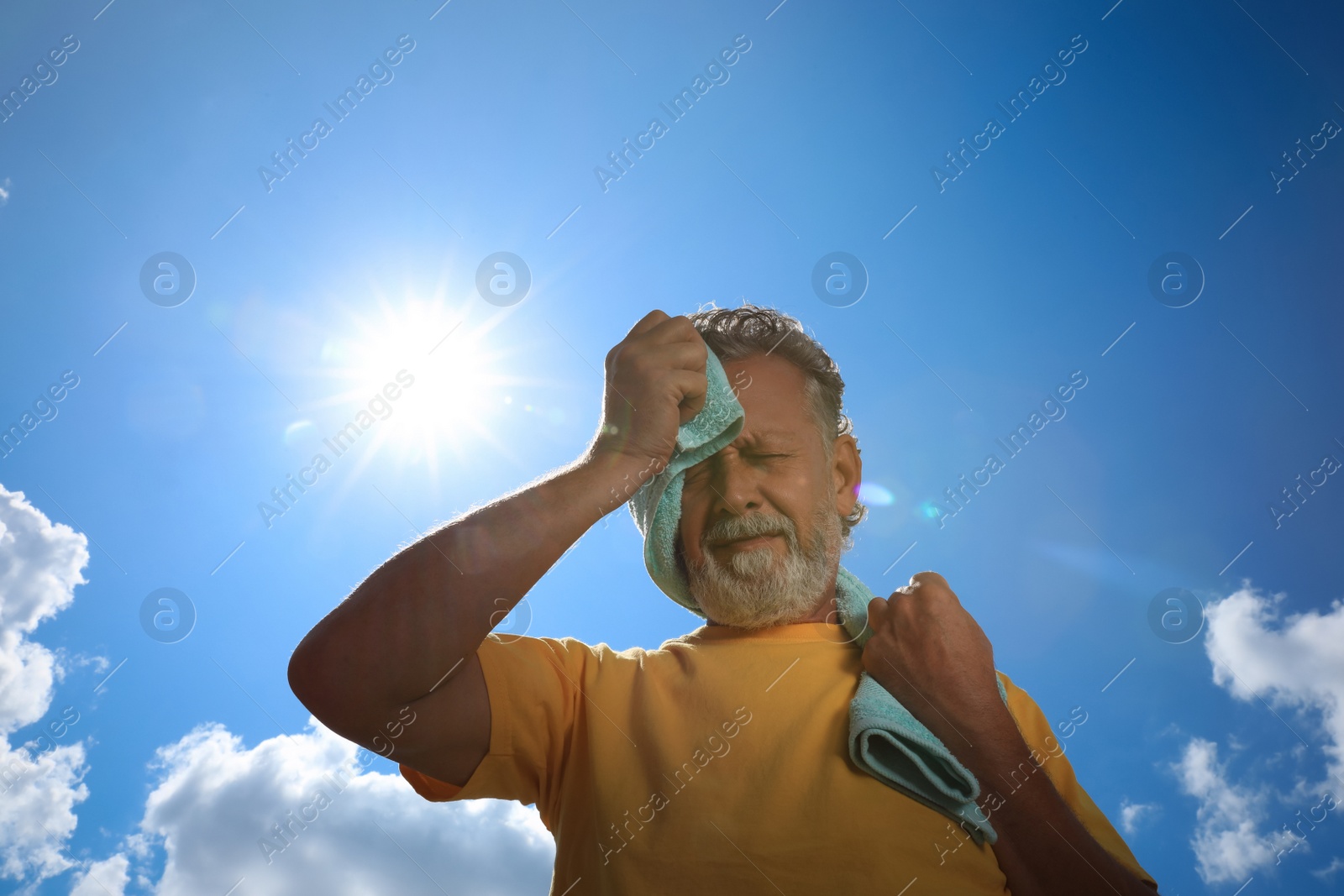 Photo of Senior man with towel suffering from heat stroke outdoors, low angle view