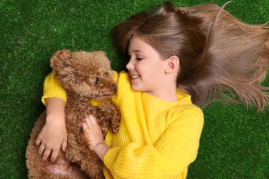 Little child with cute puppy on green grass, top view. Lovely pet