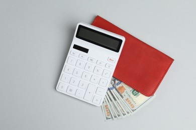 Money exchange. Dollar banknotes and calculator on gray background, top view