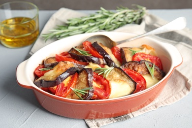 Photo of Baked eggplant with tomatoes, cheese and rosemary in dishware on table