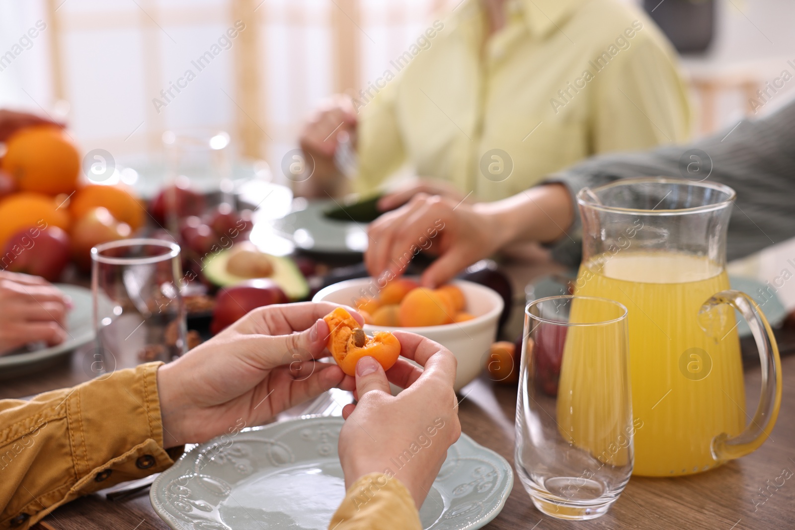 Photo of Vegetarian food. Friends eating fresh fruits at wooden table indoors, closeup