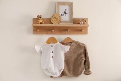 Photo of Wooden shelf with baby clothes, toys and accessories in room. Interior design