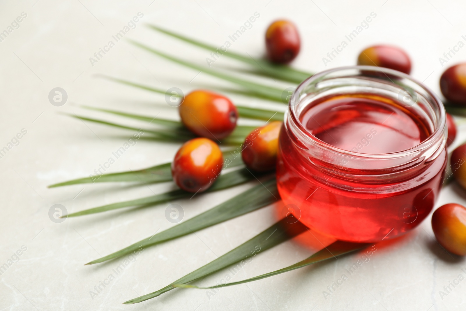 Image of Palm oil in glass jar, tropical leaf and fruits on light table. Space for text