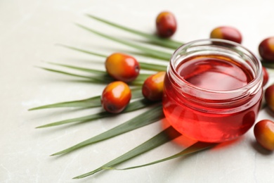 Image of Palm oil in glass jar, tropical leaf and fruits on light table. Space for text