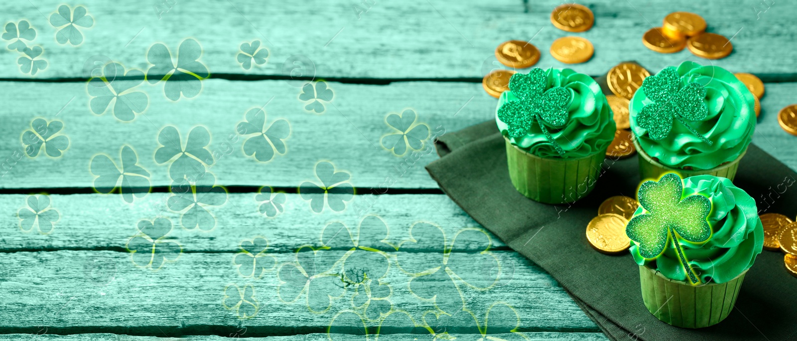 Image of St. Patrick's day. Tasty cupcakes with clover leaf toppers and cream on green wooden table, closeup. Banner design with space for text