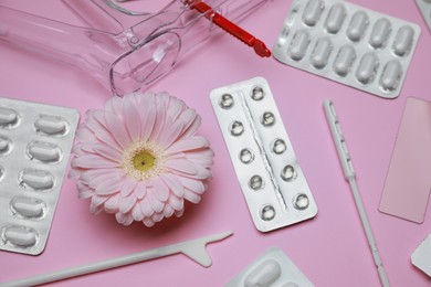 Photo of Many gynecological tools, pills and gerbera flower on pink background, above view