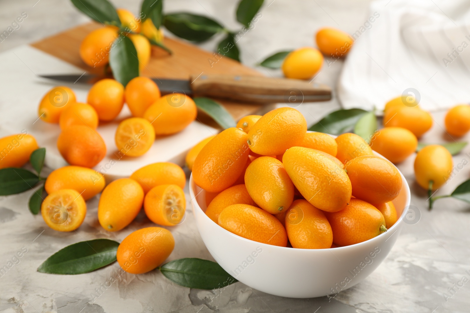 Photo of Fresh ripe kumquats in bowl on light grey table