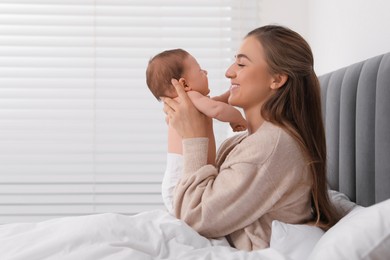 Photo of Mother holding her cute newborn baby in bed indoors, space for text