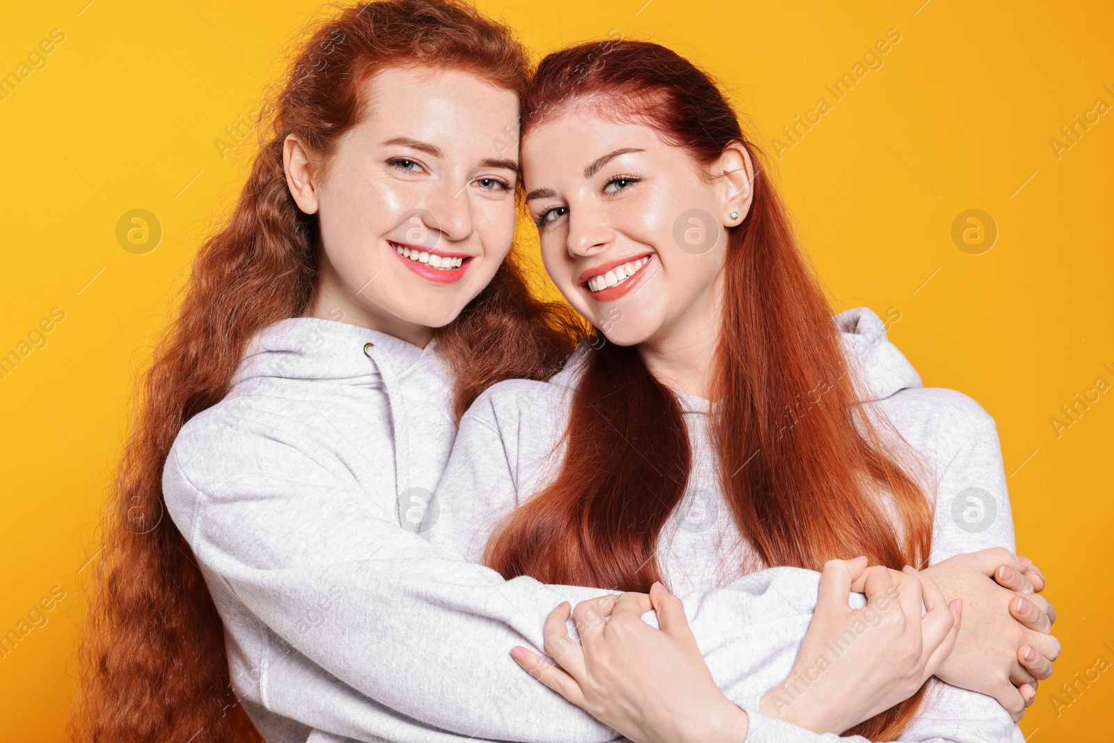 Photo of Portrait of beautiful young redhead sisters on orange background