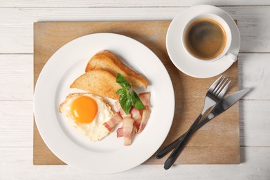 Photo of Fried egg with bacon, toasted bread and cup of coffee served for breakfast, top view