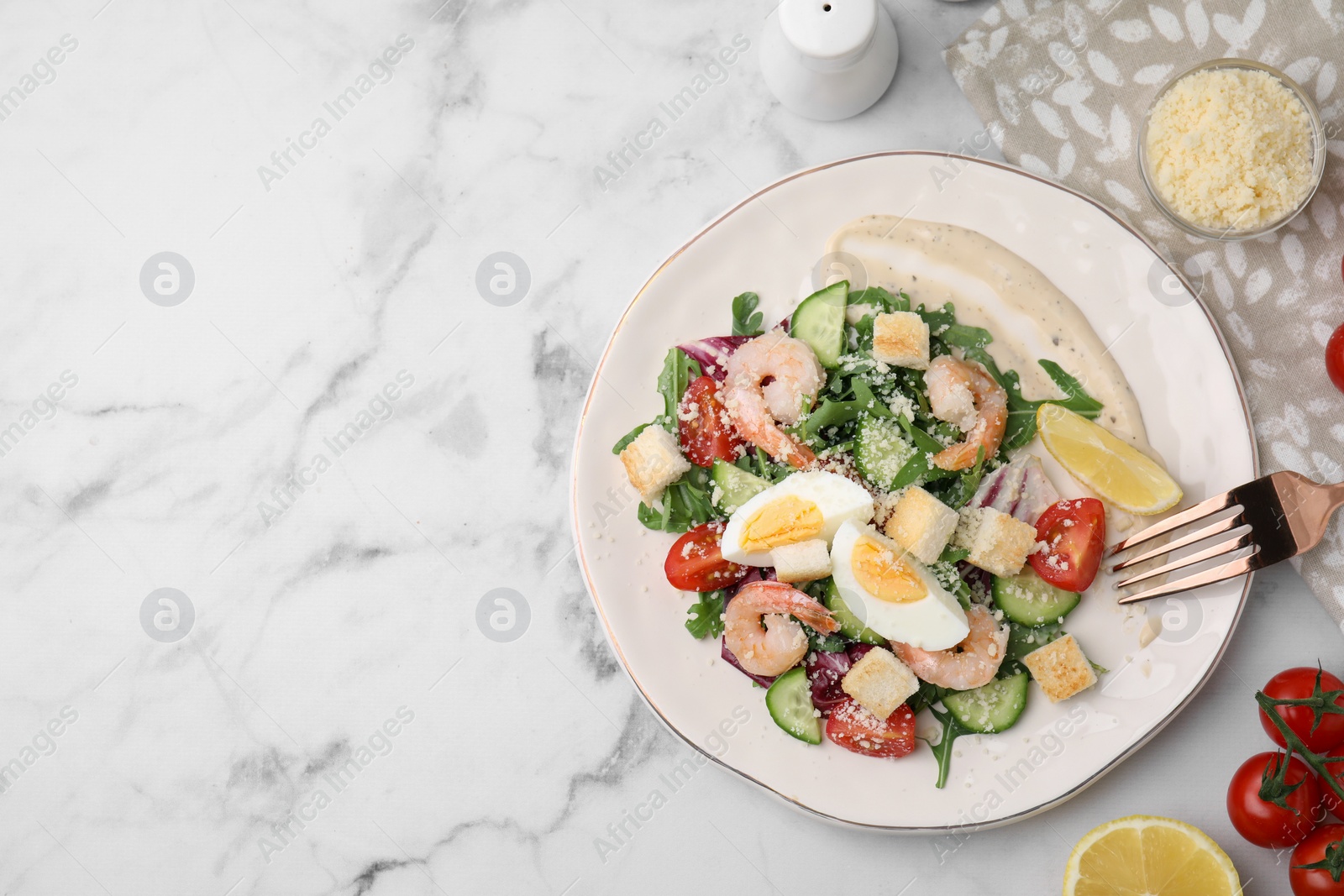 Photo of Delicious Caesar salad with shrimps and ingredients on white marble table, flat lay. Space for text