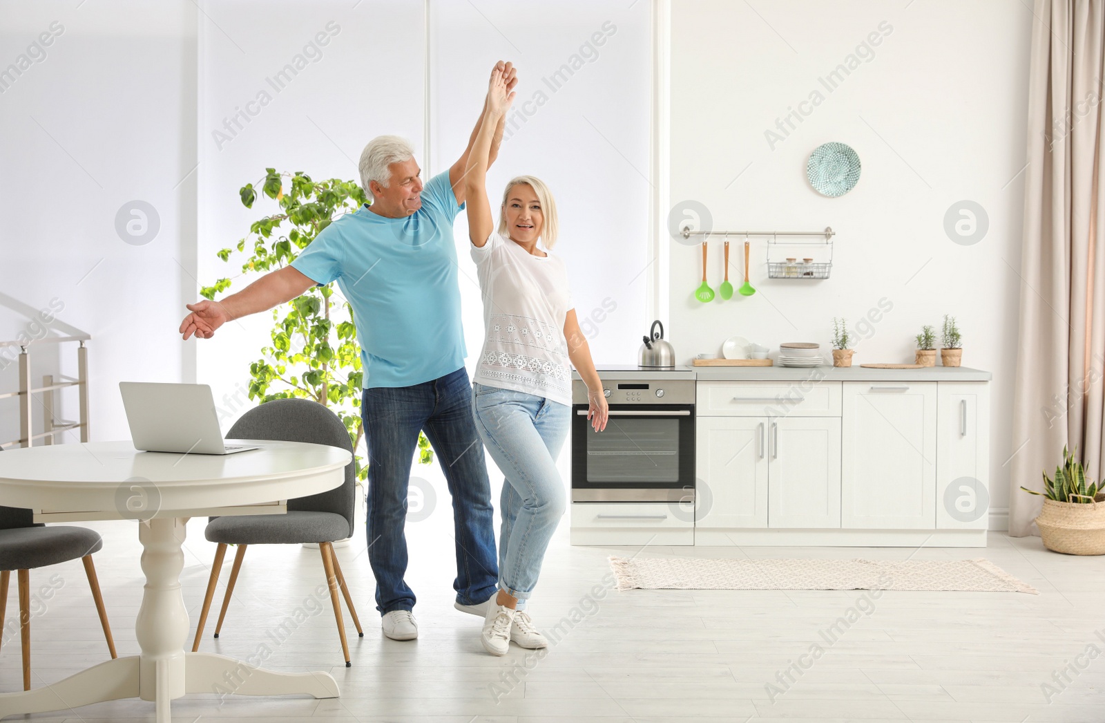 Photo of Happy mature couple dancing together in kitchen