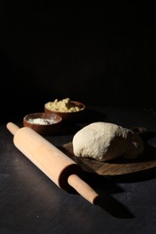 Rolling pin, flour and dough on black table