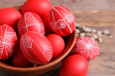 Wooden bowl with red painted Easter eggs on table, closeup