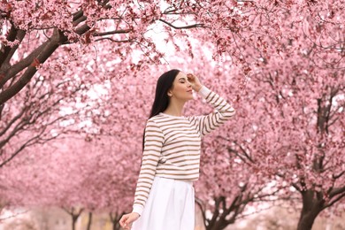 Photo of Pretty young woman in park with blooming trees. Spring look