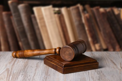 Law. Judge's gavel on wooden table against shelf with books indoors