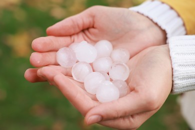 Photo of Woman holding hail grains after thunderstorm outdoors, closeup