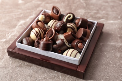 Box with different tasty chocolate candies on table