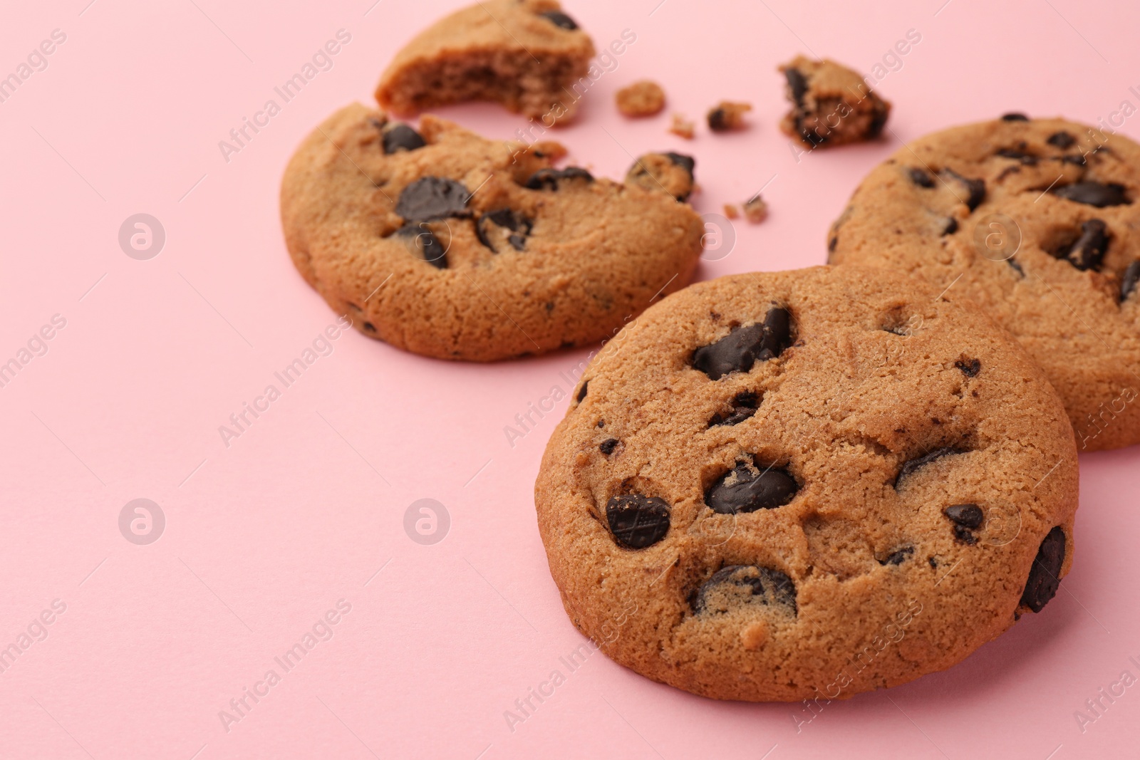 Photo of Delicious chocolate chip cookies on pale pink background, closeup