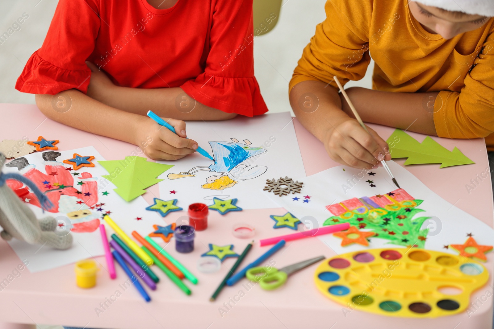 Photo of Little children drawing at table indoors, closeup. Christmas season