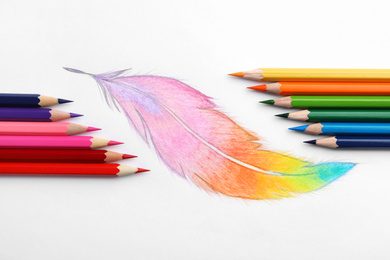 Drawing of feather and colorful pencils on white background, top view