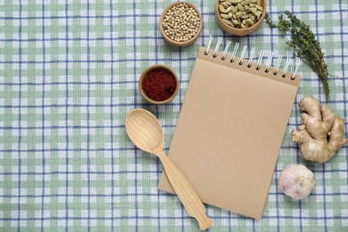 Blank recipe book and different ingredients on checkered tablecloth, flat lay. Space for text