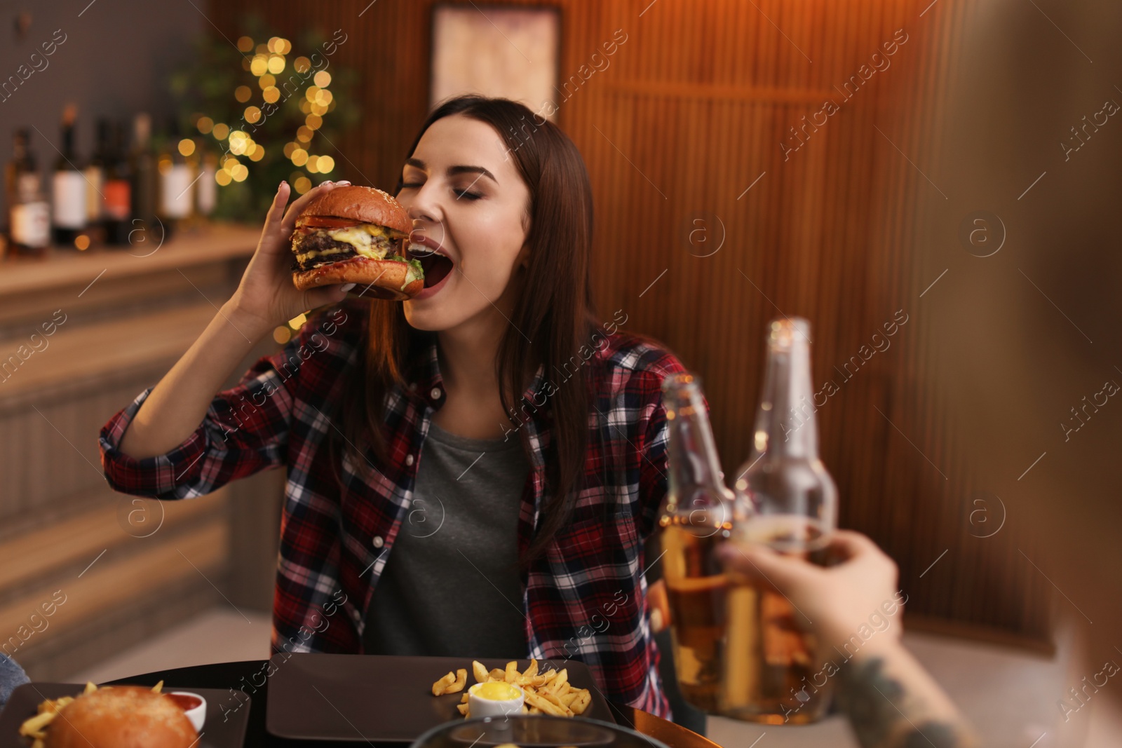 Photo of Young woman eating tasty burger in cafe