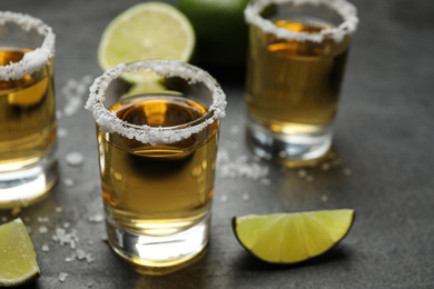 Mexican Tequila shots, lime slices and salt on grey table