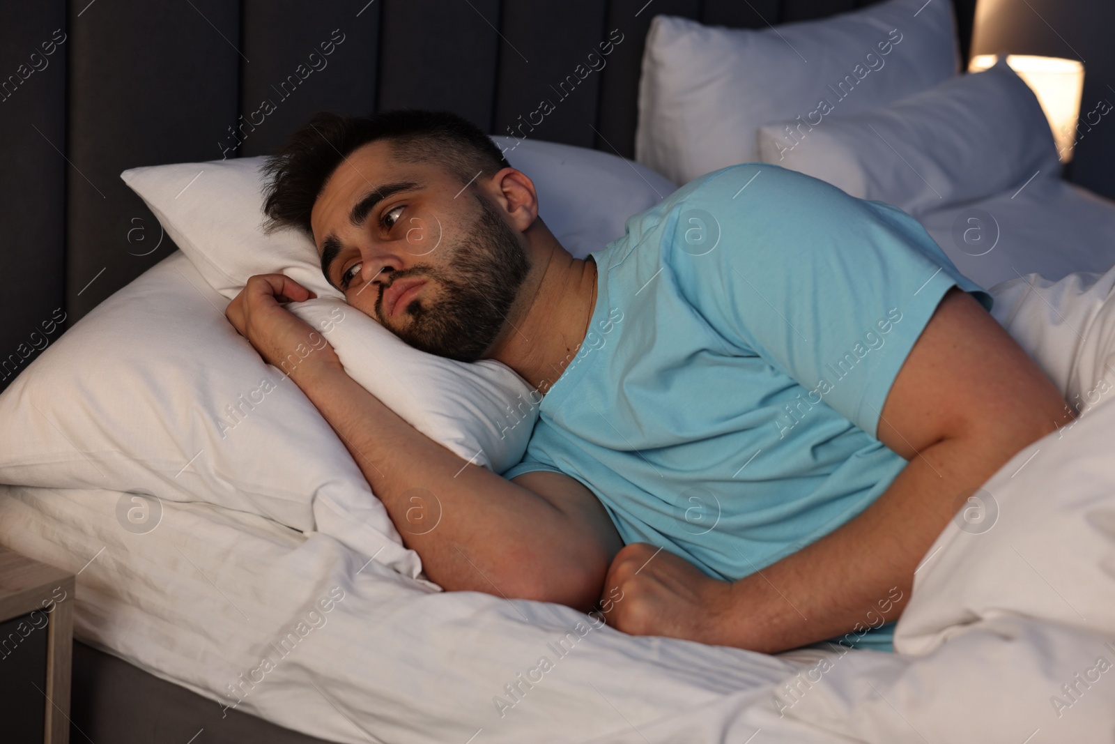 Photo of Frustrated man suffering from insomnia in bed