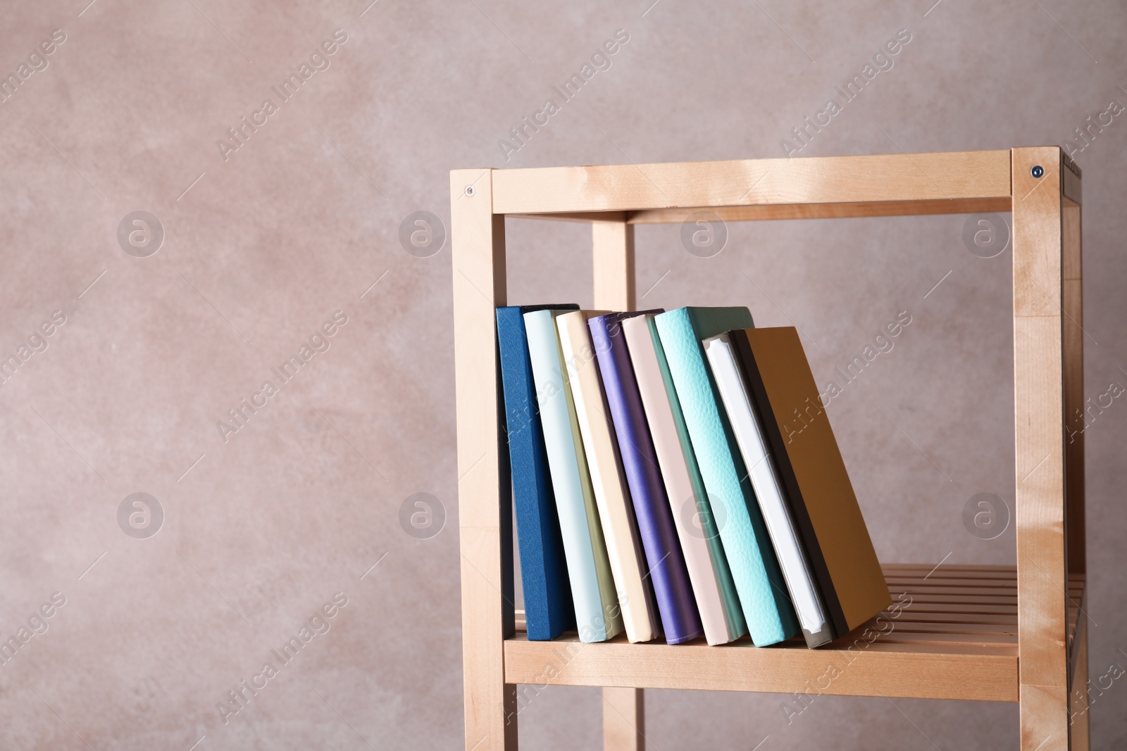 Photo of Different books on shelf against color background. Space for text