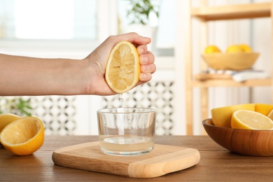 Woman squeezing lemon juice into glass bowl at table