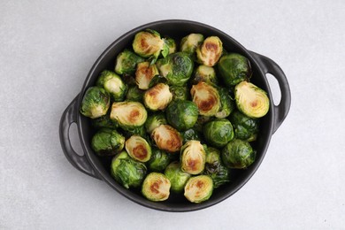 Delicious roasted Brussels sprouts in baking dish on light table, top view
