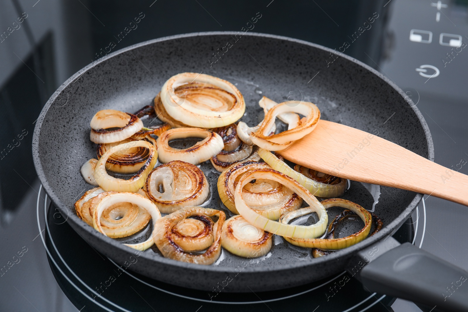 Photo of Cooking onion rings in frying pan, closeup