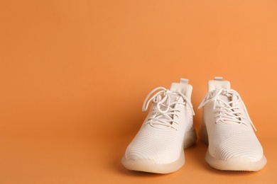 Photo of Pair of stylish sport shoes on orange background. Space for text