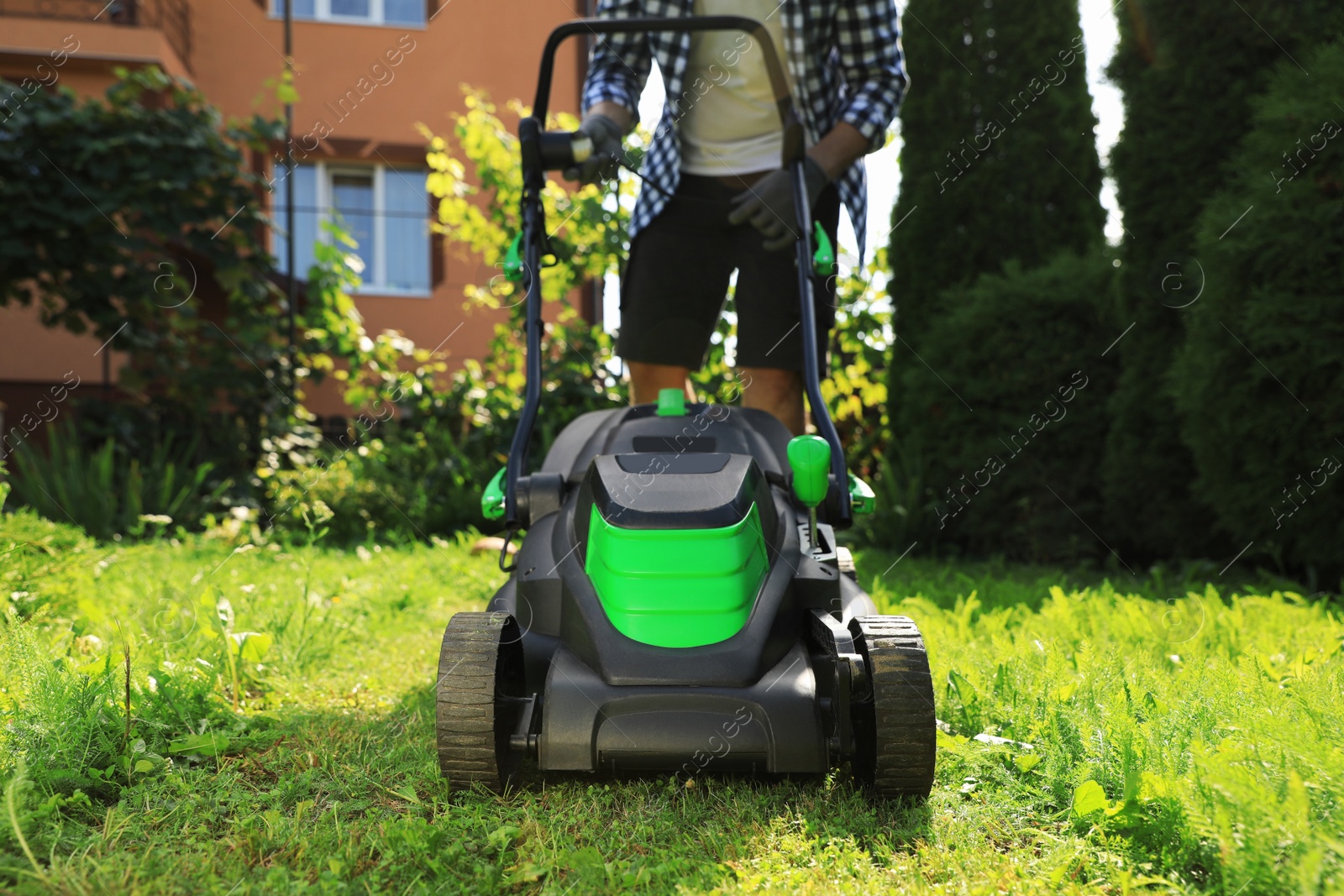 Photo of Man turning on lawn mower in garden, closeup. Cutting grass