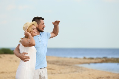 Happy romantic couple spending time together on beach, space for text