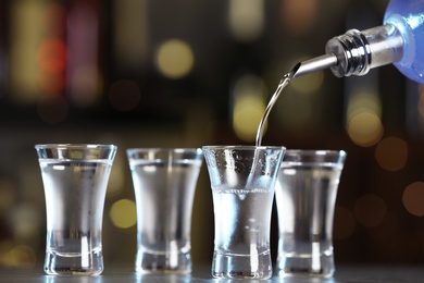 Pouring vodka from bottle into shot glass on bar counter