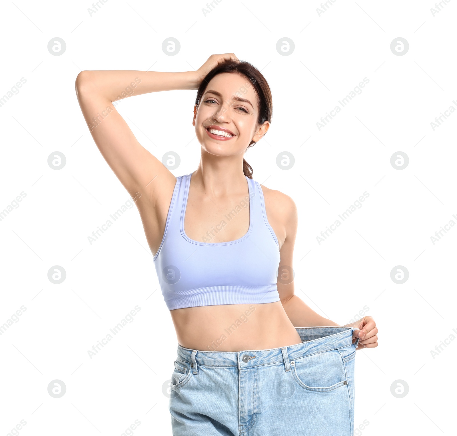 Photo of Happy young woman in big jeans showing her slim body on white background