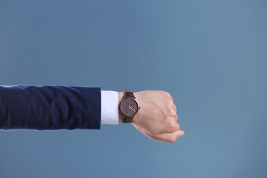 Businessman with wristwatch on color background. Time concept