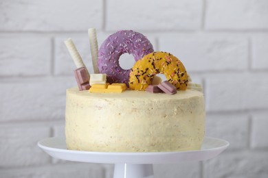 Photo of Delicious cake decorated with sweets against white brick, closeup